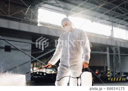 Man dressed white protective overalls spraying surface antibacterial sanitizer sprayer during quarantine 88654175