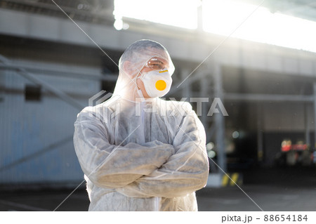 COVID-19 coronavirus doctor standing hospital parking dressed white protective overalls hazmat suit. 88654184