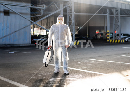 Man dressed white protective overalls spraying surface antibacterial sanitizer sprayer during quarantine Man dressed white protective overalls spraying surface antibacterial sanitizer sprayer during quarantine 88654185