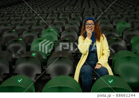 Caucasian woman cheers for a sports team at the stadium. The girl watches the match at the stadium alone. 88661244