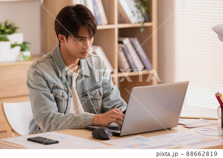 At home, a business asian man types and works online on a desk table with a laptop. At home, a business asian man types and works online on a desk table with a laptop. 88662819