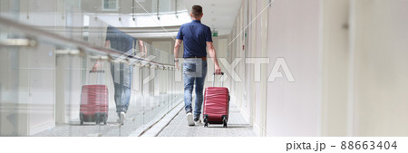 Man with suitcase walking down in hotel corridor back view 88663404