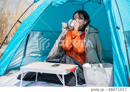 飲み物を飲んでソロキャンプを楽しむ若い女性 88671057