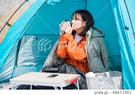 飲み物を飲んでソロキャンプを楽しむ若い女性 88671061