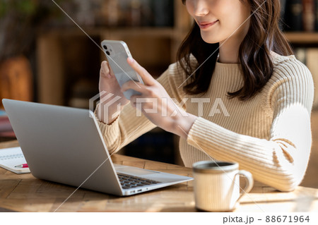 リビングでノートパソコンとスマホを使う女性【パーツカット】 88671964