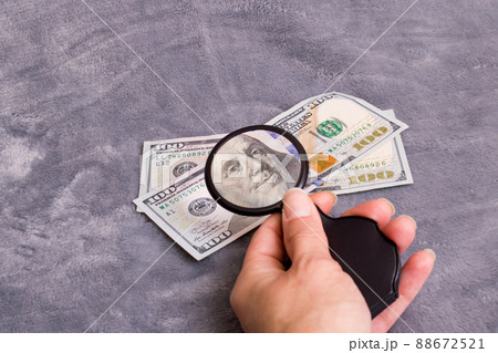 Checking dollar bill for authenticity with magnifying glass 88672521