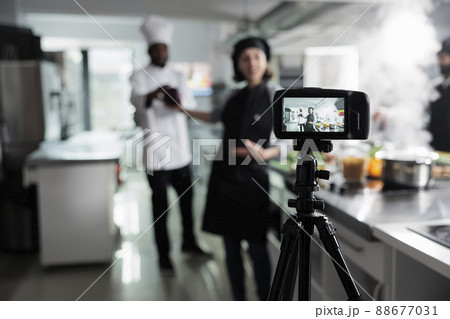 Close up of camera recording food industry workers preparing delicious gourmet dish while broadcasting. Chefs in restaurant professional kitchen filming cooking session for culinary school. 88677031
