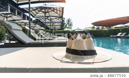 Summer holiday vacation relaxation at resort hotel swimming pool with hat and sunglasses to protect from UV sunlight on sunny day sky Summer holiday vacation relaxation at resort hotel swimming pool with hat and sunglasses to protect from UV sunlight on sunny day sky 88677550
