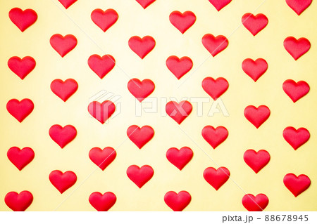 A lot of identical red silk hearts lying staggered on a yellow background. Symbol of love, tenderness and passion A lot of identical red silk hearts lying staggered on a yellow background. Symbol of love, tenderness and passion 88678945