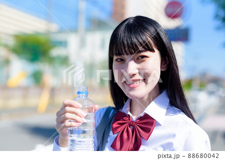 外でペットボトルの水を飲む女子高校生　ミネラルウォーター　美容　健康習慣　正面 88680042