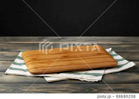Wooden board with kitchen napkin on dark wooden table Wooden board with kitchen napkin on dark wooden table 88680208