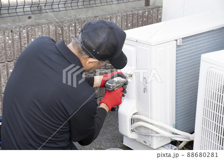 エアコンの撤収作業で室外機を外す作業員 88680281
