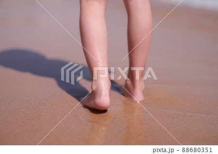 Wet bare feet walk along beach along sea closeup Wet bare feet walk along beach along sea closeup 88680351
