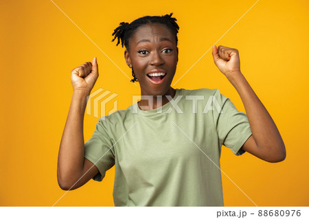 Happy african american woman looking surprised in yellow studio Happy african american woman looking surprised in yellow studio 88680976