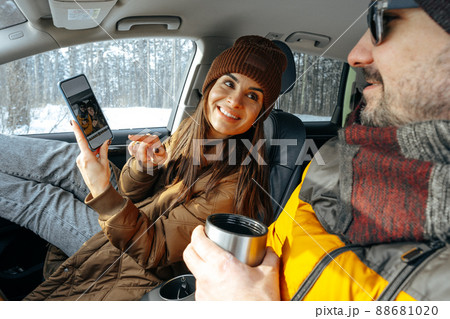 Family couple sitting in car in winter clothes iin snow forest Family couple sitting in car in winter clothes iin snow forest 88681020