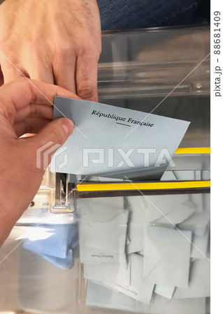 A voter throws an envelope with a candidate into the ballot box. Translation Republic of France A voter throws an envelope with a candidate into the ballot box. Translation Republic of France 88681409