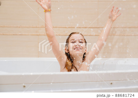 a cheerful kid girl washes and plays in the bathroom.  88681724