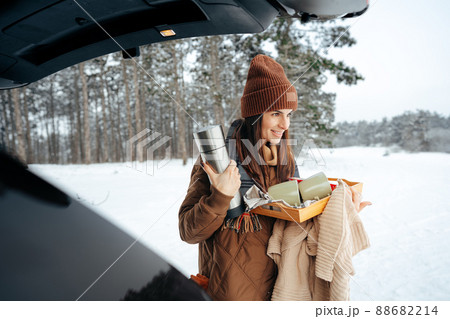 Young woman with hot drink thermos at winter forest 88682214