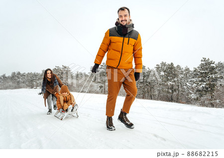 Father pulling little son on sledge in winter 88682215