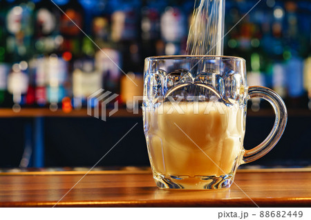 Pouring draft beer into a glass on bar background 88682449