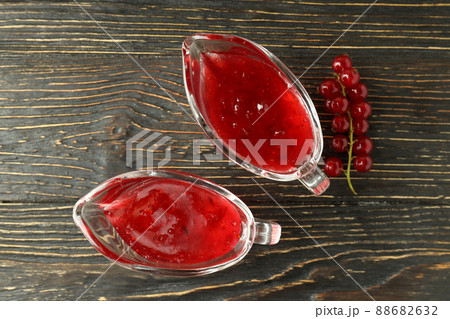 Sauce boats with cranberry sauce and cranberry on wooden background Sauce boats with cranberry sauce and cranberry on wooden background 88682632