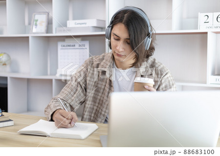 Asian man taking notes in notebook while studying online in laptop at home, Video chat, Online communication , Stay home, New normal, Distance learning, Social distancing, Learn online. Asian man taking notes in notebook while studying online in laptop at home, Video chat, Online communication , Stay home, New normal, Distance learning, Social distancing, Learn online. 88683100