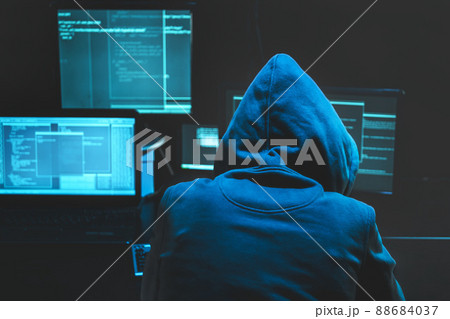 Hacker using computer for organizing massive data breach attack on goverment servers. Hacker in dark room surrounded computers 88684037