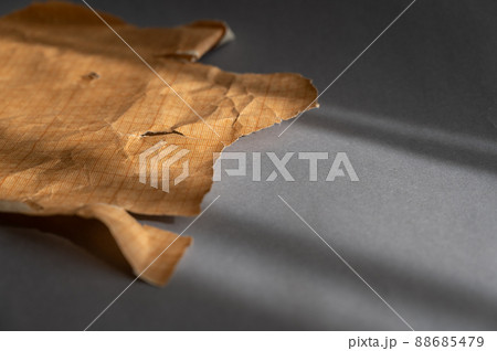 Millimeter or scale-coordinate drawing paper marked into squares. A piece of brown crumpled paper against a gray background. Millimeter or scale-coordinate drawing paper marked into squares. A piece of brown crumpled paper against a gray background. 88685479