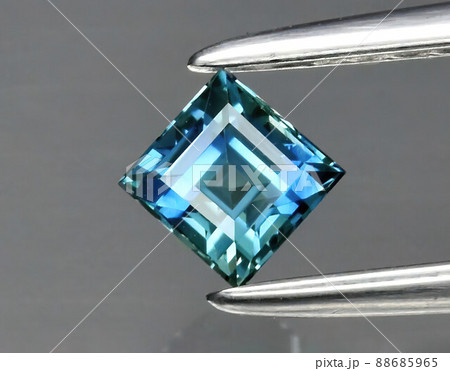 Natural gemstone blue sapphire in tongs on a gray background 88685965