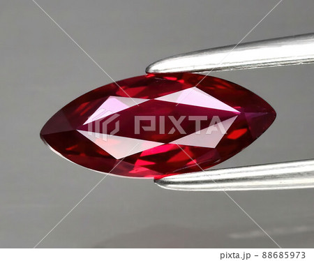 Natural gemstone red ruby in tongs on a gray background 88685973