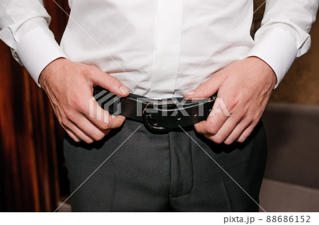 The groom tightens his belt. A man holding his hands on his belt The groom tightens his belt. A man holding his hands on his belt 88686152