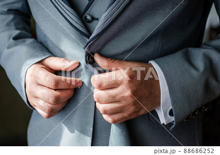 The man fasten a button on his jacket. The groom fasten a button on his jacket The man fasten a button on his jacket. The groom fasten a button on his jacket 88686252