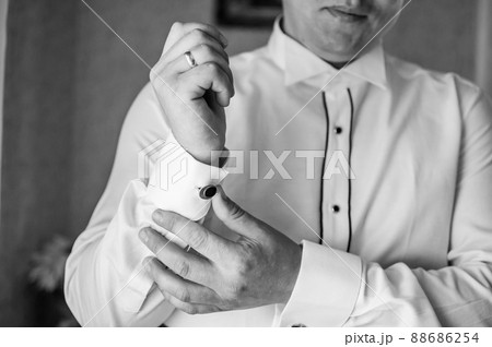 The man fastens the cufflink on the sleeve of his shirt. The groom fastens a button on the sleeve of his shirt The man fastens the cufflink on the sleeve of his shirt. The groom fastens a button on the sleeve of his shirt 88686254