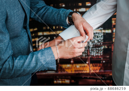 The man fastens the cufflink on the sleeve of his shirt. The groom fastens a button on the sleeve of his shirt The man fastens the cufflink on the sleeve of his shirt. The groom fastens a button on the sleeve of his shirt 88686259