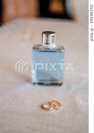 A pair of gold wedding rings, a jar of men's perfume on the background A pair of gold wedding rings, a jar of men's perfume on the background 88686260