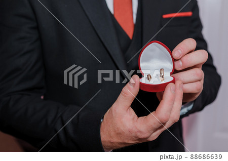 Red box with gold wedding rings in the hands of a man Red box with gold wedding rings in the hands of a man 88686639