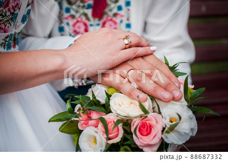 hands of newlyweds with wedding rings on a wedding bouquet with white and pink roses hands of newlyweds with wedding rings on a wedding bouquet with white and pink roses 88687332