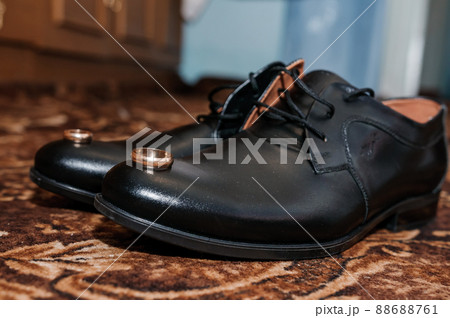 Gold wedding rings on black shoes on the floor. Accessories for the groom on the wedding day Gold wedding rings on black shoes on the floor. Accessories for the groom on the wedding day 88688761