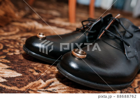 Gold wedding rings on black shoes on the floor. Accessories for the groom on the wedding day 88688762