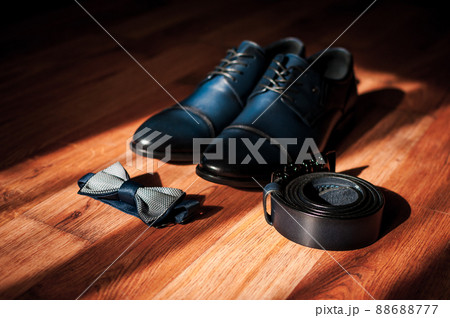 Blue leather men's shoes, bow tie and belt lie on the floor. Groom's accessories Blue leather men's shoes, bow tie and belt lie on the floor. Groom's accessories 88688777