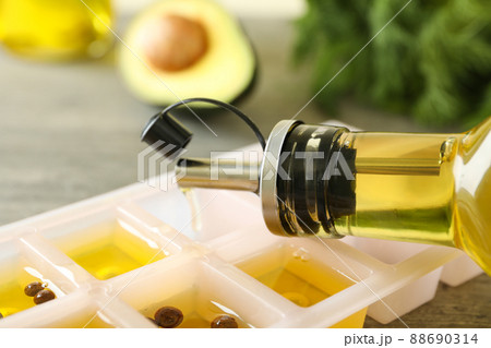 Oil is pouring from the bottle into ice tray, close up Oil is pouring from the bottle into ice tray, close up 88690314