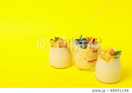 Glass jars with peach yogurt on yellow background 88691198