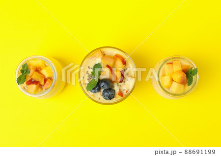 Glass jars with peach yogurt on yellow background 88691199