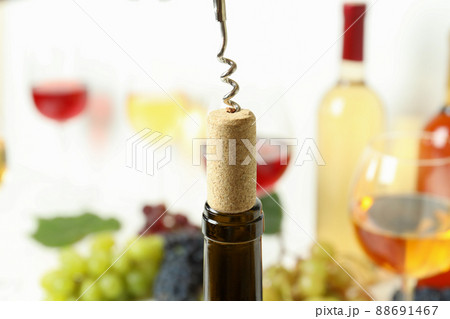 Corkscrew with cork, and wine bottle, close up 88691467
