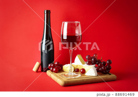 Board with wine, cheese and grape on red background Board with wine, cheese and grape on red background 88691469