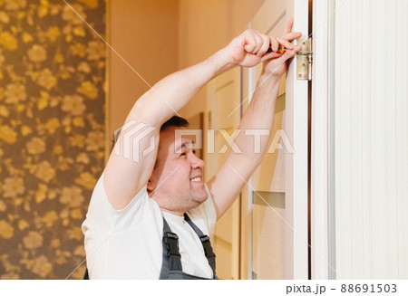 a male repairman repairs the door. handyman service. a male repairman repairs the door. handyman service. 88691503