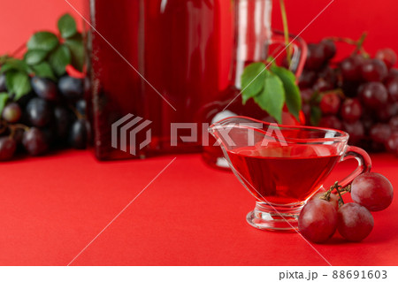 Concept of grape vinegar on red background Concept of grape vinegar on red background 88691603