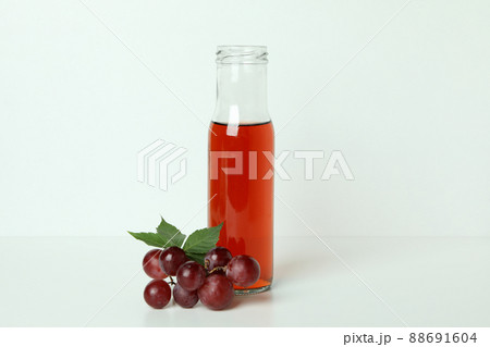 Bottle of vinegar and grape on white table Bottle of vinegar and grape on white table 88691604