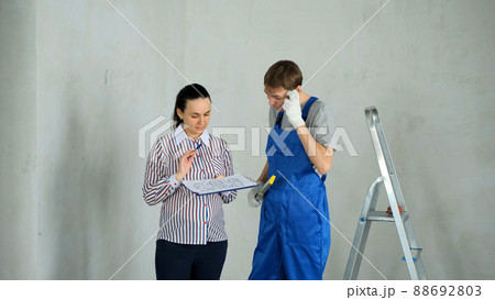 Young Woman and Worker Discussing Blueprint and Details of Future Renovation Indoors. Repair Home Concept Young Woman and Worker Discussing Blueprint and Details of Future Renovation Indoors. Repair Home Concept 88692803