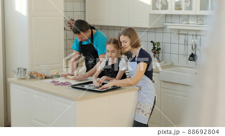 Family of Three Doing Bakery Cooking at Home. Mother, Father and Little Daughter Making Cookies Together Family of Three Doing Bakery Cooking at Home. Mother, Father and Little Daughter Making Cookies Together 88692804
